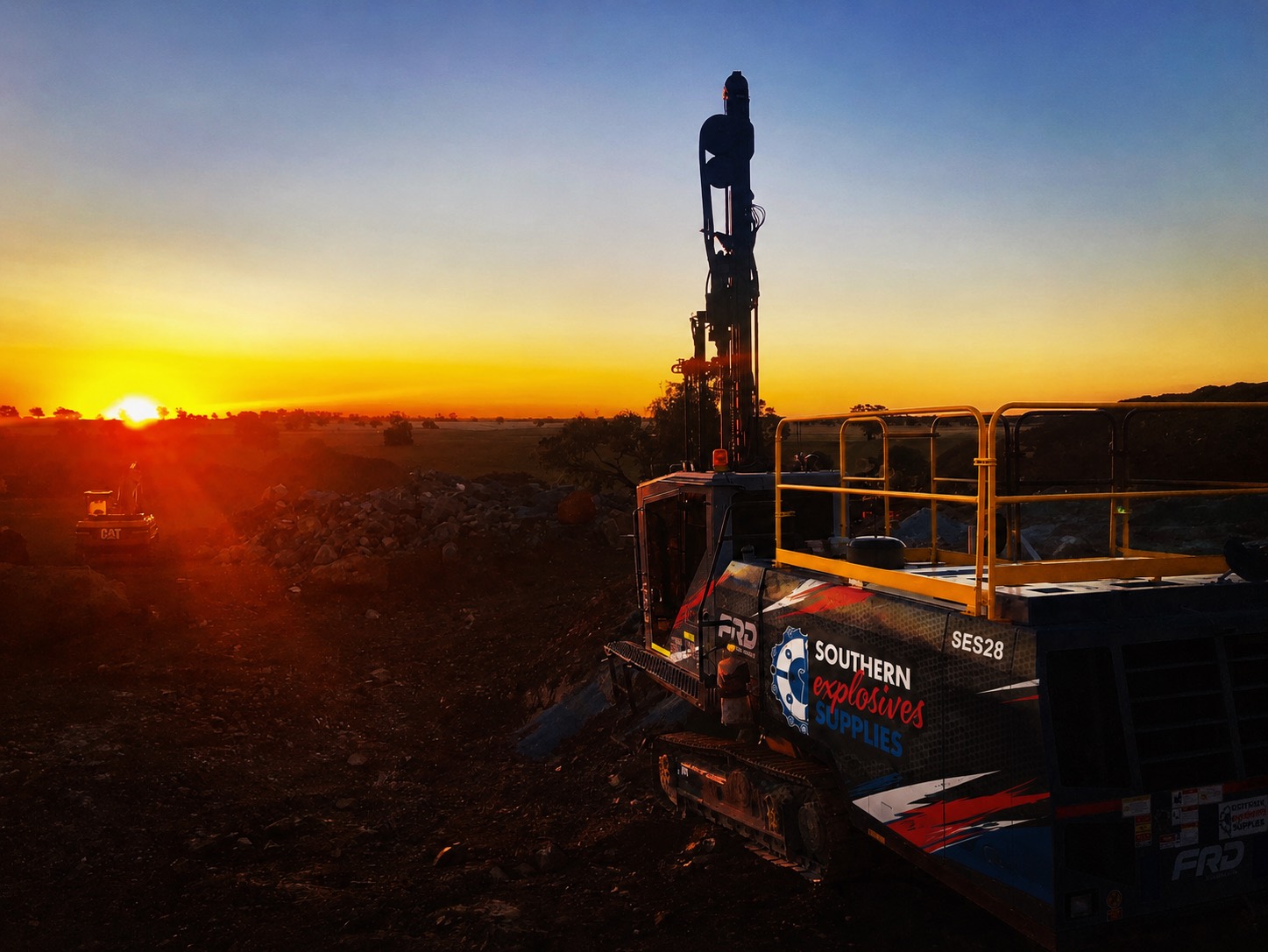 Drill rig lit up at sunset