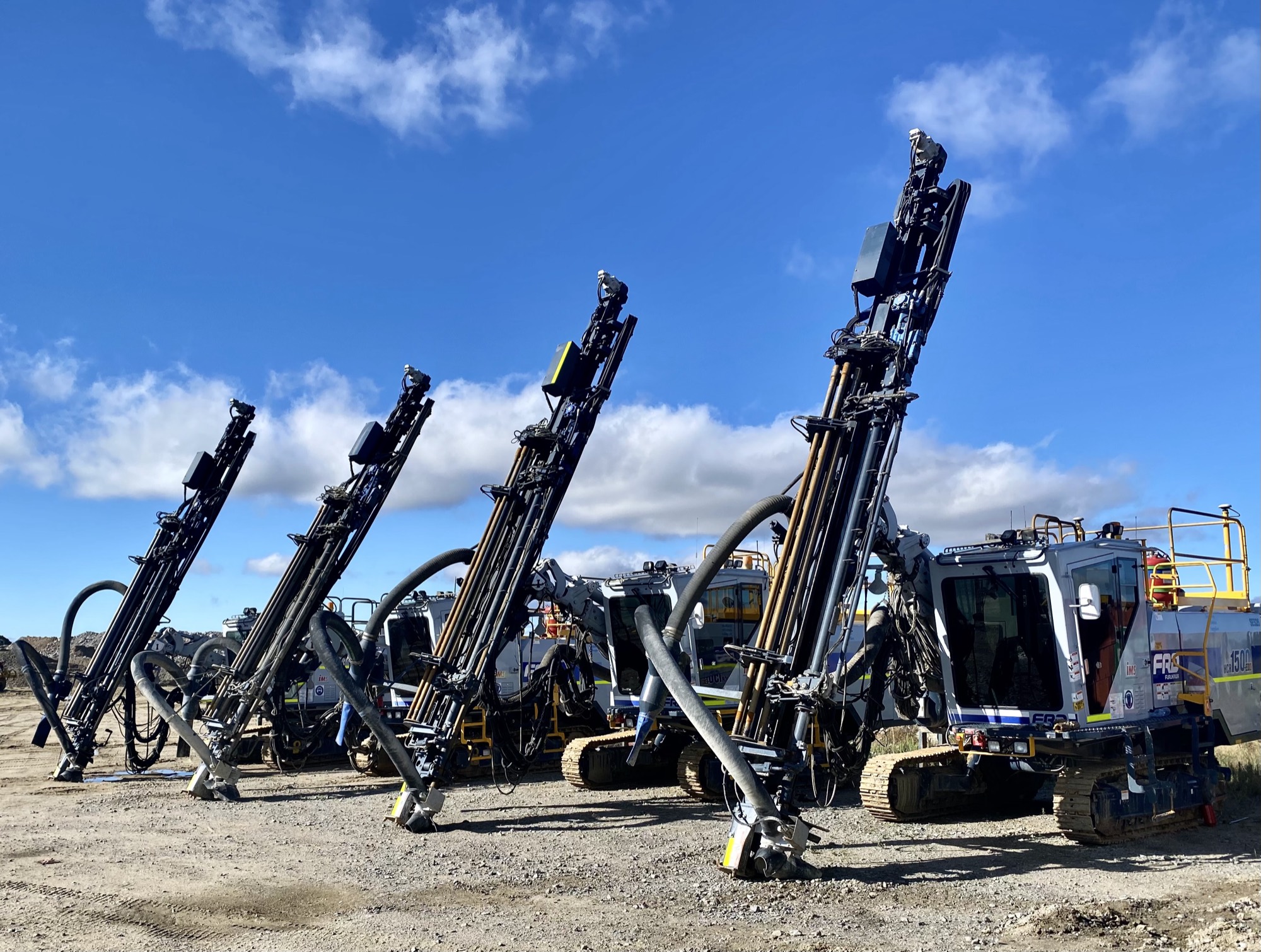 A line of drill rigs with masts raised ready for hire